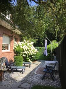 a garden with two benches and an umbrella at Haus Claudia in Schneverdingen