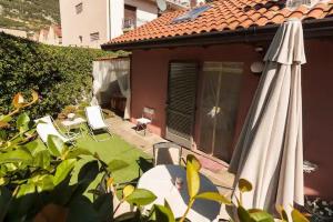a patio with an umbrella and chairs and a house at Il Gelsomino di Ossuccio in Ossuccio