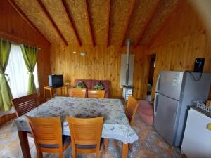 a kitchen and dining room with a table and a refrigerator at Cabañas borde rio in Villarrica