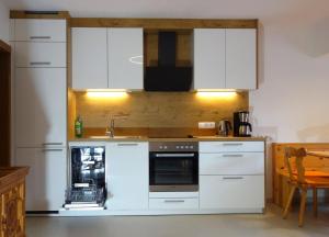 una cocina con armarios blancos y fregadero en Ferienwohnung Mariner Inzing en Inzing