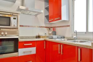a kitchen with red cabinets and a microwave at SunShine Buen Pastor in Córdoba