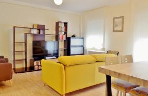 a living room with a yellow couch and a television at SunShine Buen Pastor in Córdoba