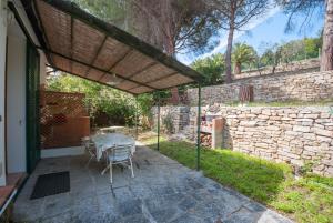 Un patio con mesa y sillas y un muro de piedra. en Villaggio la Serra - Appartamenti con giardino, en Marina di Campo