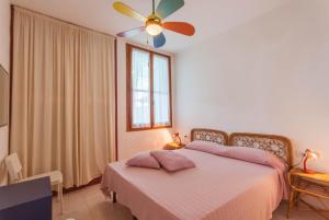 Un dormitorio con una cama y un ventilador de techo. en Villaggio la Serra - Appartamenti con giardino, en Marina di Campo
