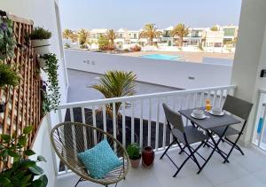 balkon ze stołem i krzesłami oraz basen w obiekcie Oasis View Lanzarote w Costa Teguise