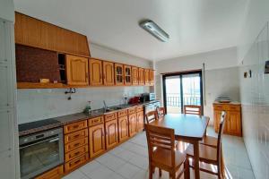 a kitchen with wooden cabinets and a table with chairs at Half Way Nazaré - Fátima - NSA-T2 in Marrazes