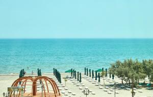 a beach with a roller coaster and umbrellas at Hotel Excelsior Mamaia Nord in Mamaia Nord