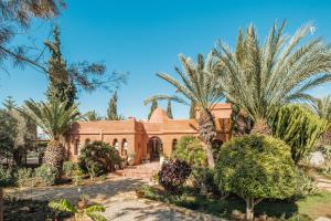 a house with palm trees in front of it at Le Jardin des Douars in Ghazoua