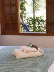 a stack of towels sitting on top of a bed at Pousada Lagoa do Rosa in Praia do Rosa
