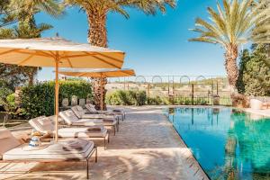 a pool with lounge chairs and umbrellas next to a swimming pool at Le Jardin des Douars in Ghazoua