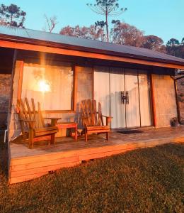 a cabin with rocking chairs on a wooden deck at Sunset Serrano Chalés in Urubici