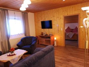 een woonkamer met een bank, een tafel en een televisie bij Ferienwohnung - Haus Monika in Philippsreut