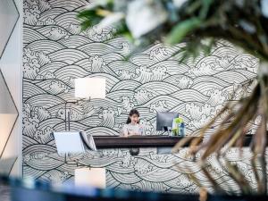 a woman sitting at a desk in an office with a mural at InterContinental Phuket Resort by IHG in Kamala Beach