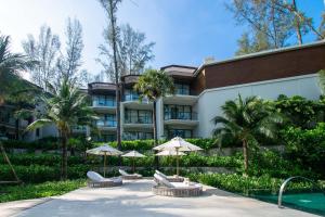 a hotel with chairs and umbrellas in front of a building at InterContinental Phuket Resort by IHG in Kamala Beach