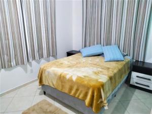 a bedroom with a bed with yellow sheets and blue pillows at Pousada Souza in Florianópolis