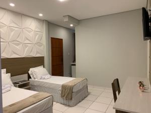een hotelkamer met 2 bedden en een tafel bij Hotel Lider in Paranaguá