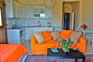 a living room with an orange couch and a kitchen at Ktima Dafnes in Nafplio
