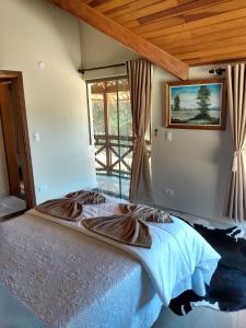 - une chambre avec un grand lit en face d'une fenêtre dans l'établissement Casa de fino acabamento e conforto em Monte verde, à Monte Verde