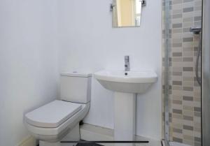 a white bathroom with a toilet and a sink at 35 mins to central London. 3 bedrooms. 2 bathrooms with garden in London