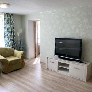 a living room with a flat screen tv and a chair at fantasy park in Ventspils