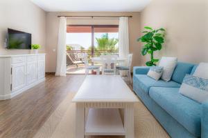 a living room with a blue couch and a table at Vitalclass Lanzarote Resort in Costa Teguise