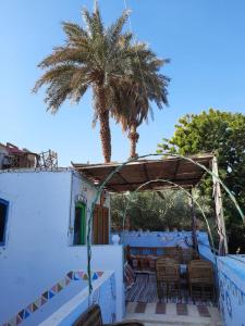 a patio with a table and a palm tree at Aswan Nubian House in Aswan