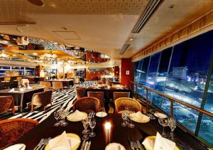 a restaurant with tables and chairs and a large window at APA Hotel Kanazawa Ekimae in Kanazawa