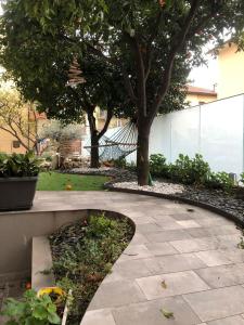 un giardino con un sentiero in pietra e un albero di Appartamento Spotorno con ampio terrazzo attrezzato anche con angolo cottura a Spotorno