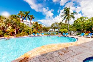 a large swimming pool with blue chairs and palm trees at La Brisa 108N in Key West