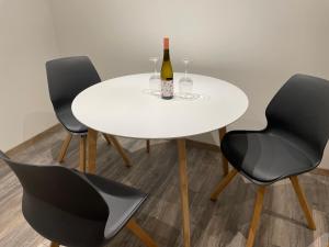 una mesa blanca con 2 sillas negras y una botella de vino en Linus und seine Ferienwohnungen en Heldrungen