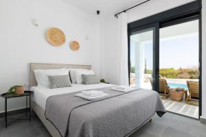 a white bedroom with a bed and a balcony at Seasand Villa in Lachania