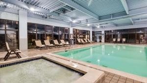 a pool in a building with chairs and tables at Best Western Historic Area in Williamsburg