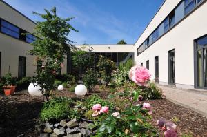 a garden in front of a building with flowers at Sporthotel Borussia Düsseldorf in Düsseldorf