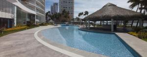a swimming pool in a resort with a thatch roof at Camino Al Mar with Amazing View of the Ocean, Beach and Pool in Mazatlán