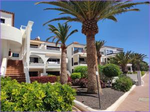 a building with palm trees in front of it at Pebble beach apartamento, Amarilla golf in San Miguel de Abona