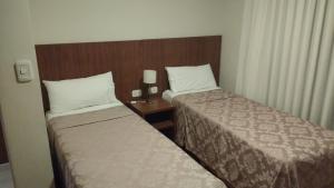 a hotel room with two beds and a wooden headboard at 11 Peyret Rent Aparts in Colón