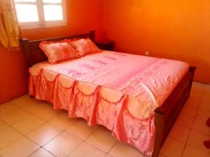 ein Schlafzimmer mit einem Bett mit orangefarbenen Wänden und einem Fenster in der Unterkunft TULEAR APPARTEMENTS CHAMBRES VILLAs in Toliara