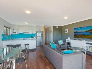 a living room with a couch and a kitchen at Pacific Pines Unit 5 in Narooma
