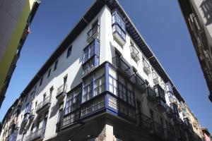 ein hohes weißes Gebäude mit Fenstern und blauem Himmel in der Unterkunft Casual Gurea in Bilbao