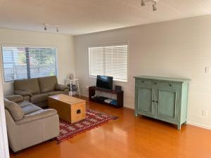 a living room with a couch and a tv at Hahei Beach House - 3 Bedroom in Hahei