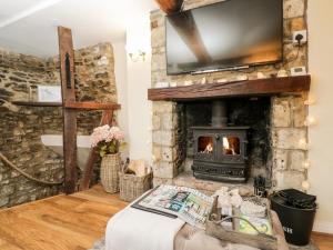 a living room with a stone fireplace and a tv at Corner Cottage in Malmesbury