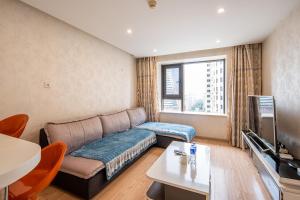 Tianjin Mengxiangjia Loft Hotel Apartment في تيانجين: غرفة معيشة مع أريكة وتلفزيون