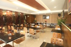 ein Restaurant mit Tischen und Stühlen und einem Fernseher in der Unterkunft Favor Hotel Makassar City Center By LIFE in Makassar