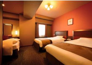 a hotel room with two beds and a window at Hotel Monte Hermana Sendai in Sendai