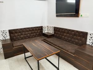 a bench with a table and a tv on the wall at CHINTA HARAN REST HOUSE in Deoghar
