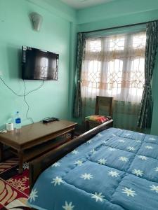 a bedroom with a bed and a table and a television at B&B Homestay in Darjeeling