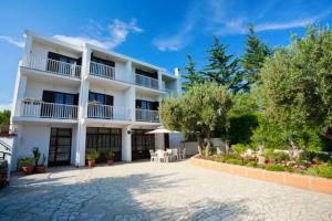 a large white building with a patio in front of it at Rooms Amfora in Krk