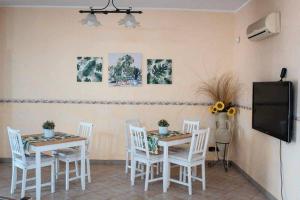 a dining room with white chairs and a table and a tv at Dimora Di Campagna in Portella di Mare