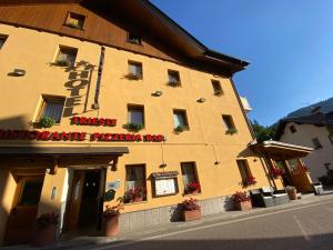 d'un grand bâtiment jaune avec un panneau. dans l'établissement Hotel Trieste, à Tarvisio