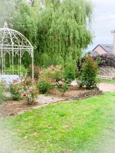 un jardín con cenador blanco y flores en Isabelle's Rosegarden, en Beckerich